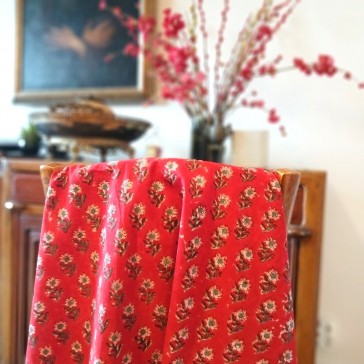 Coton indien petites fleurs répétitives roses sur fond rouge.