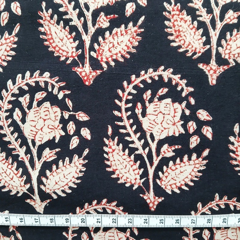 Indienne motif répété de fleurs grèges cernées de rouille sur fond noir.