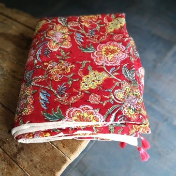 Plaid fleuri sur fond rouge doublé de gaze de coton écru pompons rose et ouatine.